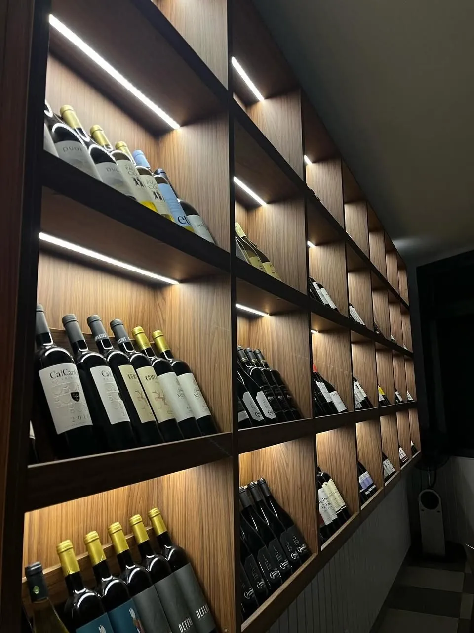 Garrafeira em madeira com iluminação embutida, num bar de vinhos