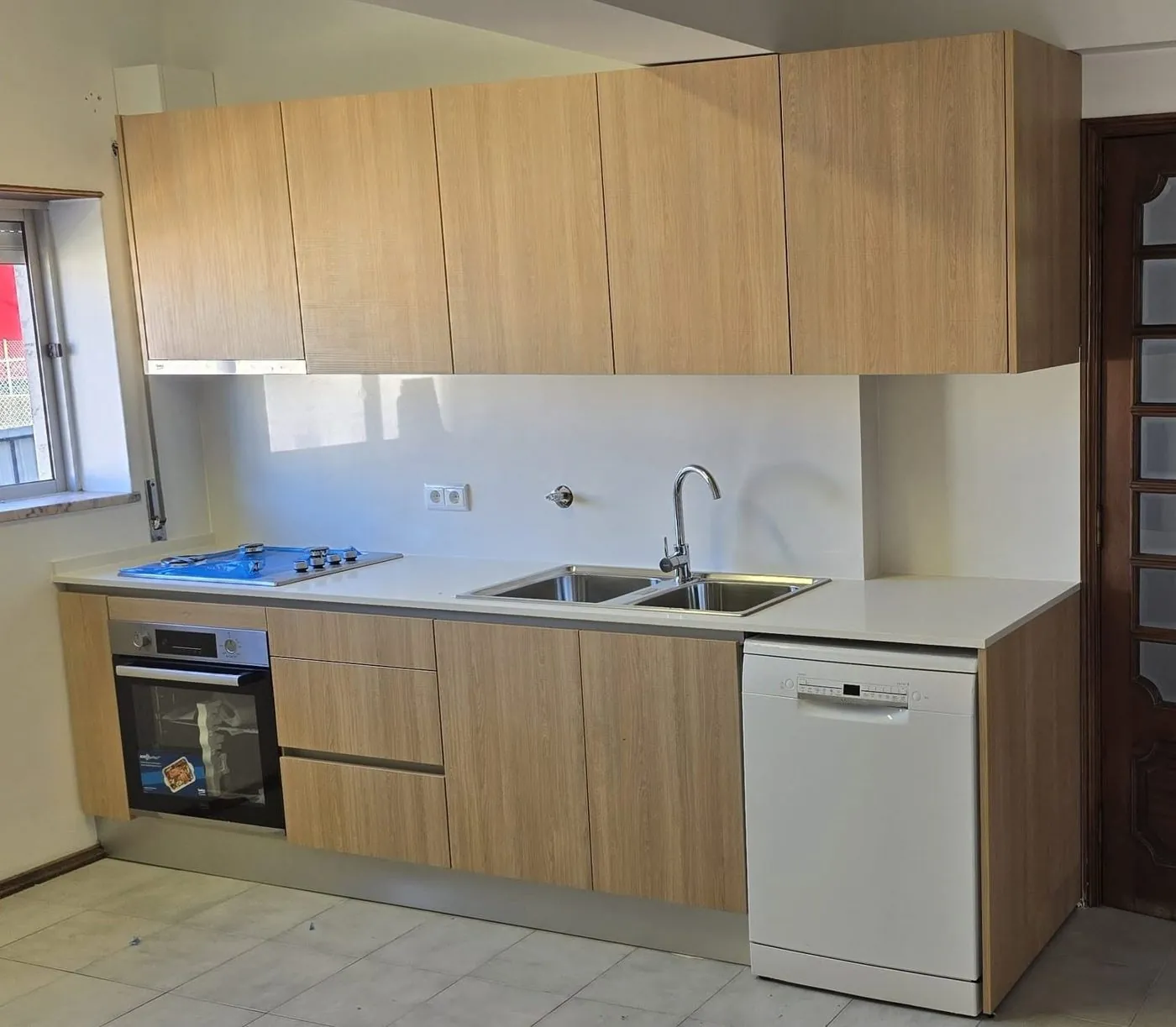 Cozinha em madeira clara com eletrodomésticos encastrados